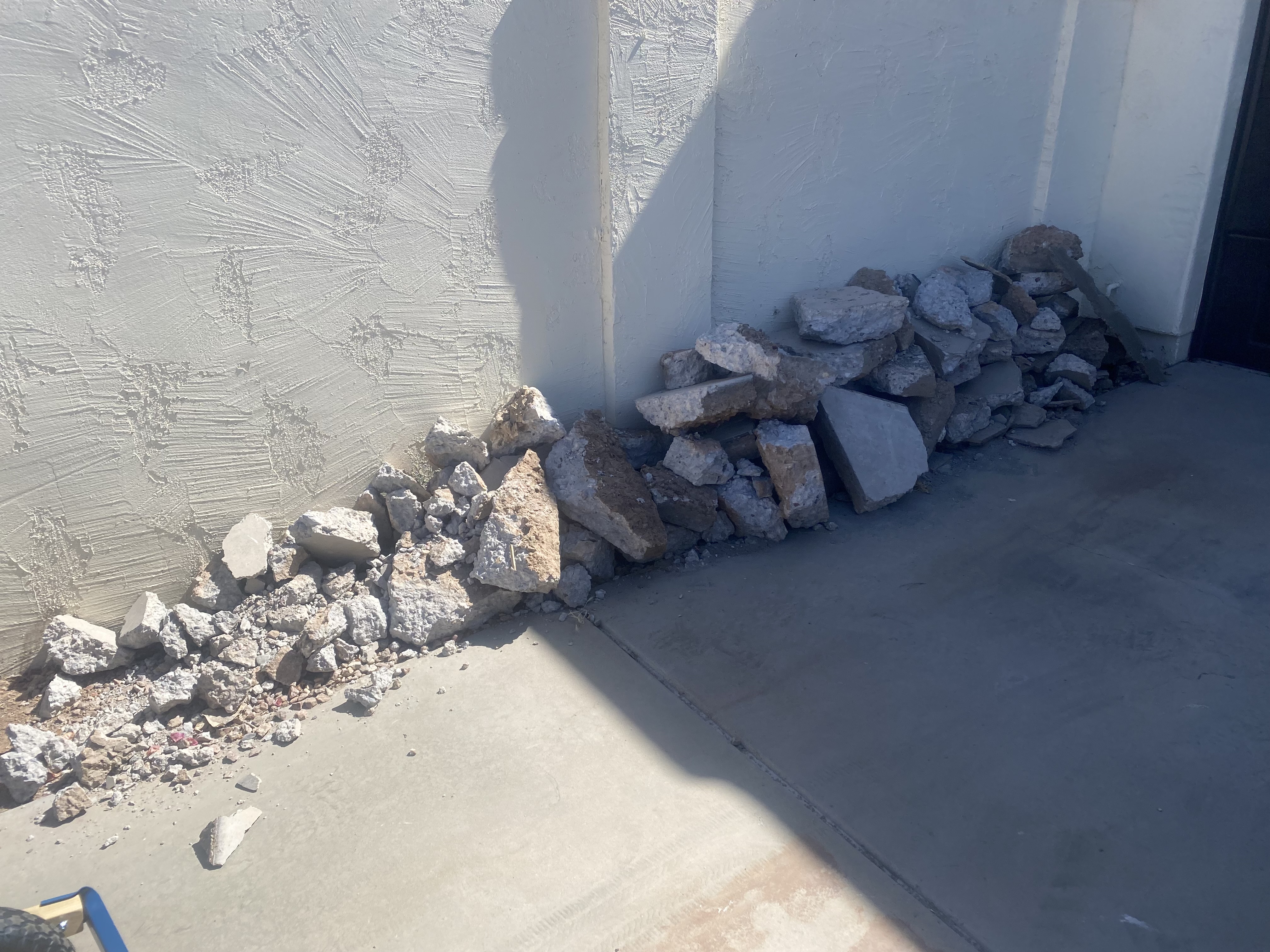 Row of broken concrete and block staged along a wall for pickup