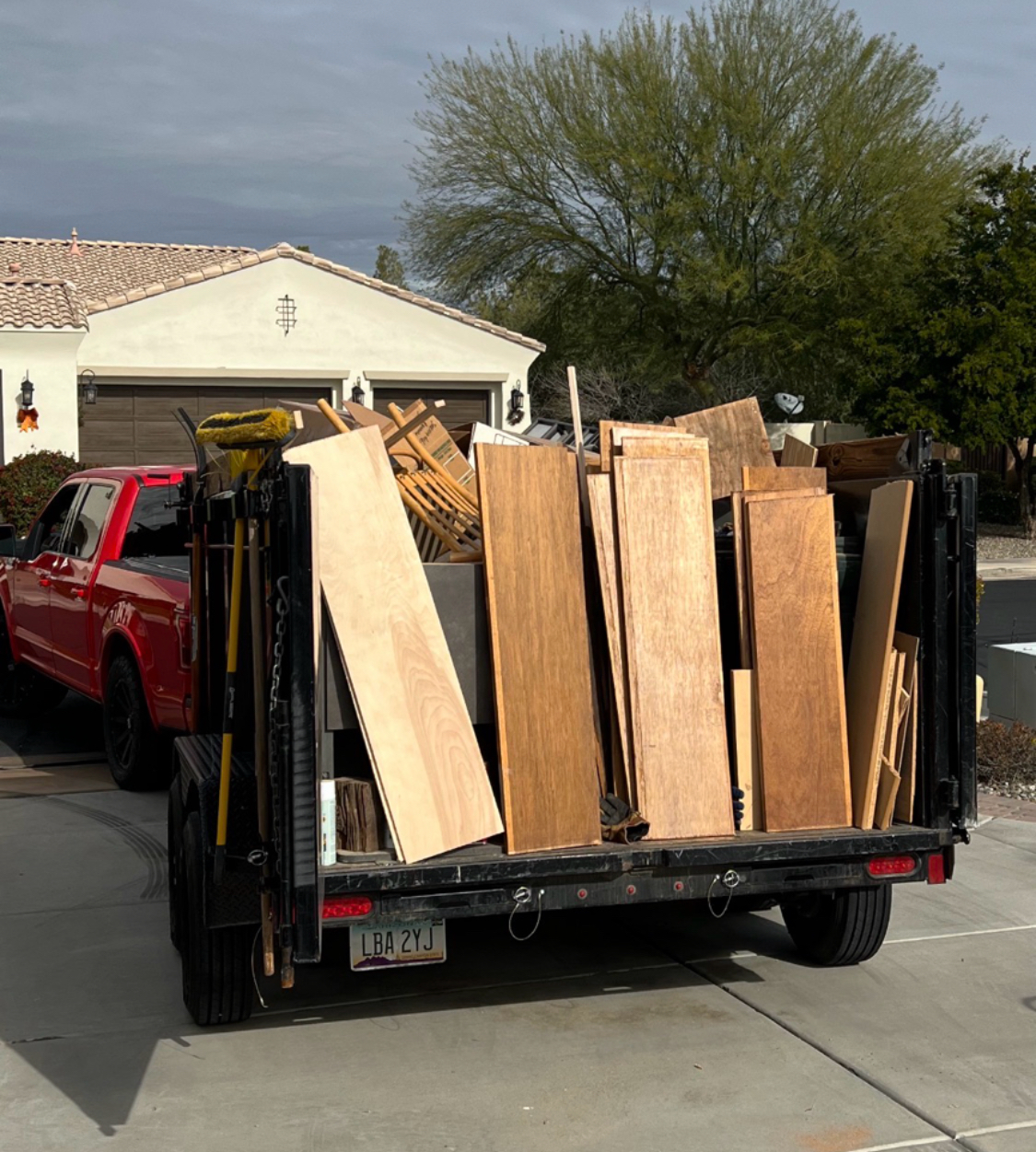 Dump trailer loaded to the top with wood panels and household junk